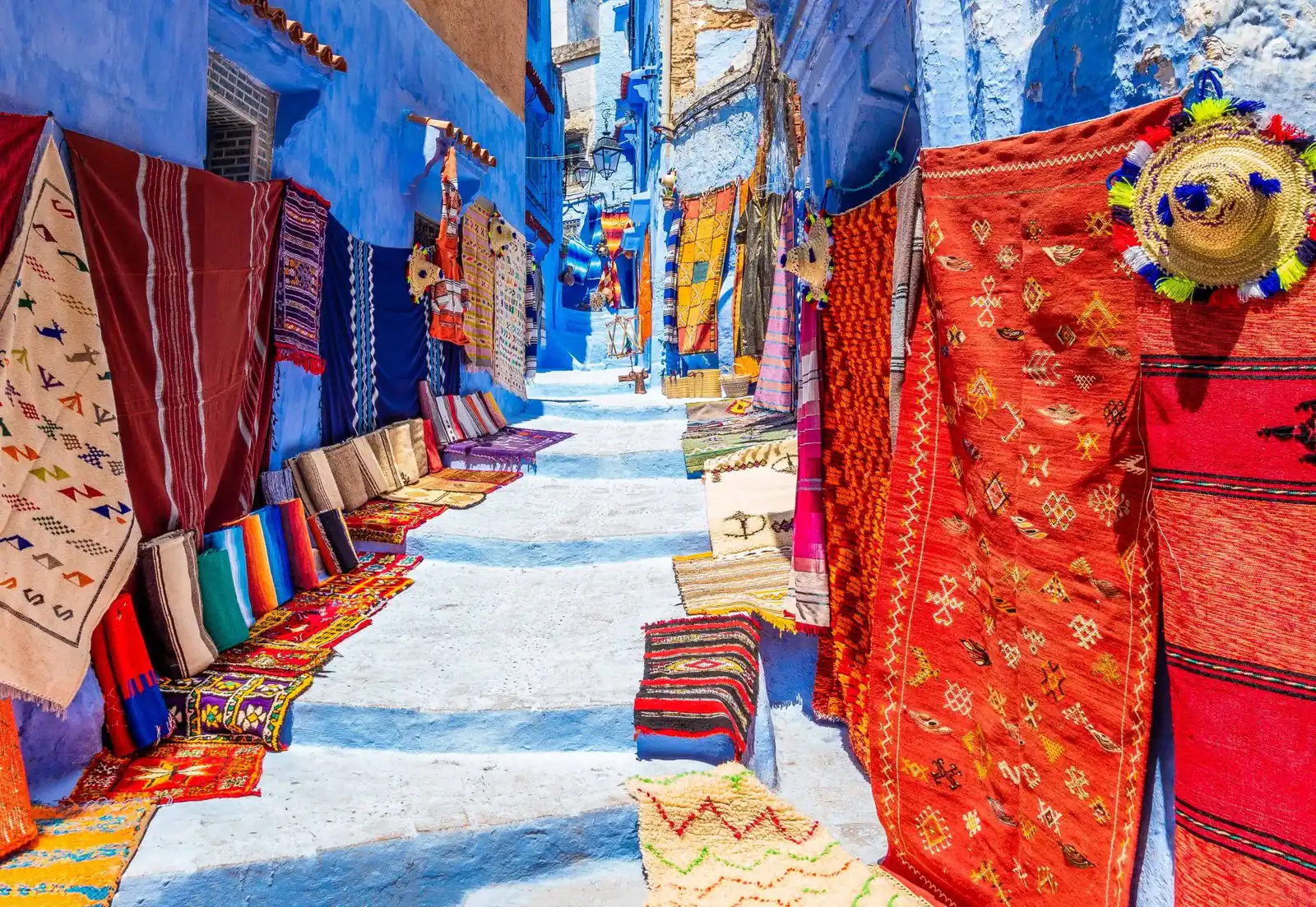 Via blu di Chefchaouen con tappeti e coperte colorate appesi ai muri