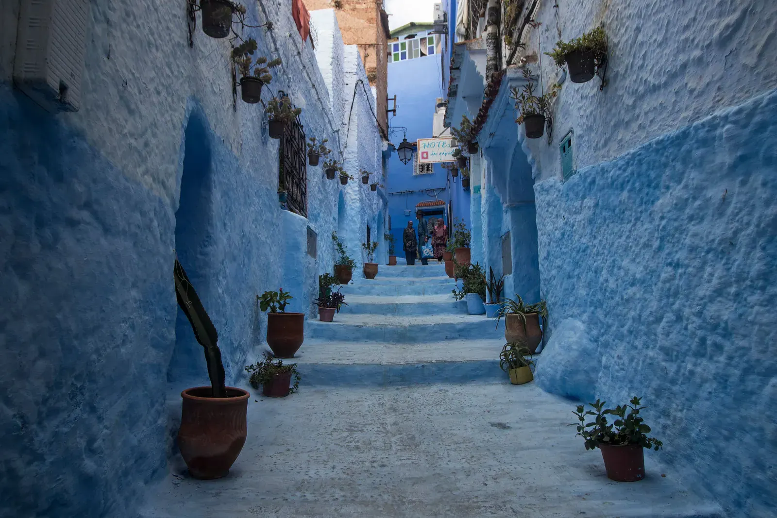 Vicolo a gradini con vasi di fiori tra muri azzurri nella medina di Chefchaouen