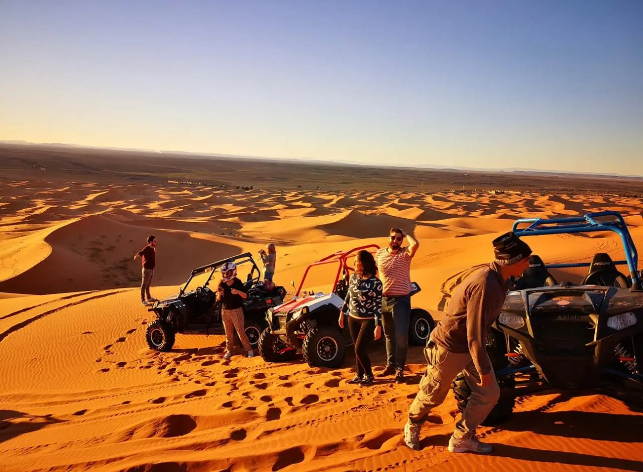 Buggy e viaggiatori in cima alle dune al tramonto