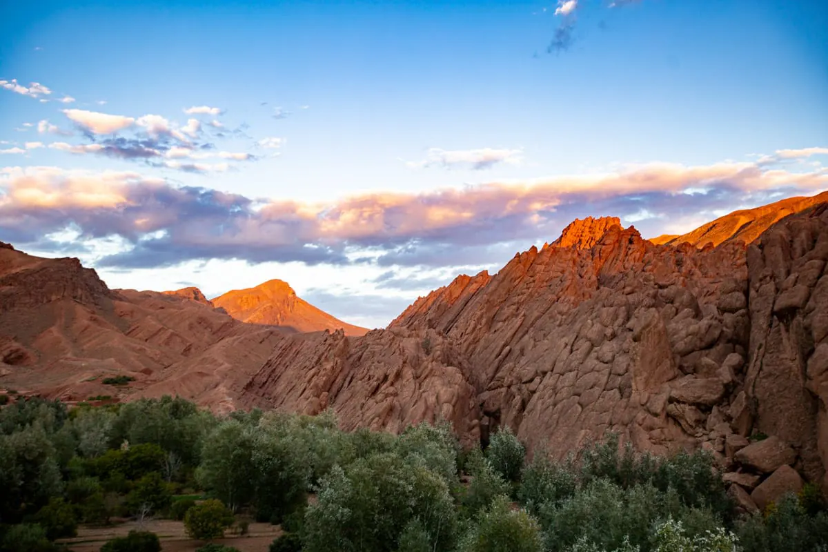 Montagne di roccia rossastra sopra il verde della valle del Dades, al tramonto