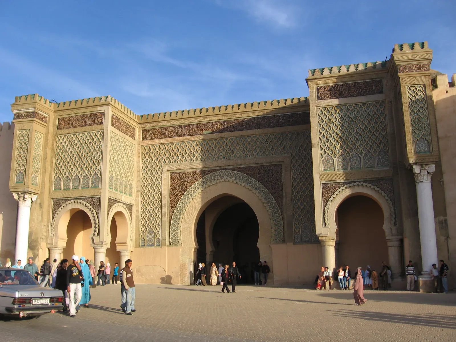 La porta Bab Mansour a Meknes, decorata con piastrelle verdi, con gente che passeggia davanti